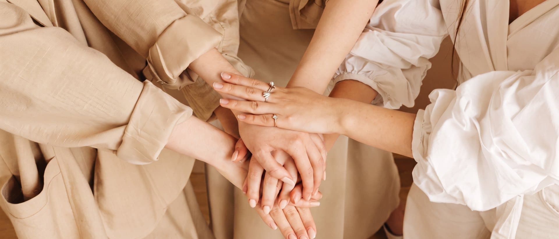 Four women standing in a circle with their hands stacked together.